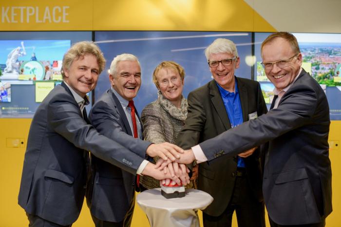 mehrere Personen drücken auf einen Knopf